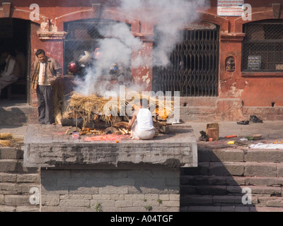 PASUPATINATH NEPAL November Man tending a cremation on one of the Ghats at this site of the Holy Temple of Lord Shiva Stock Photo