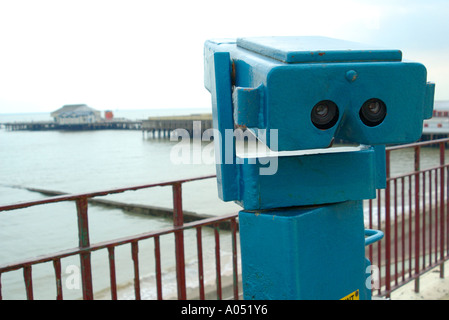 Beach binoculars and view of the sea and pier on the seafront at Clacton-on-Sea, Essex, England, UK Stock Photo