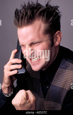 angry man on phone with hands clenched into a fist and snarling look on his face Stock Photo
