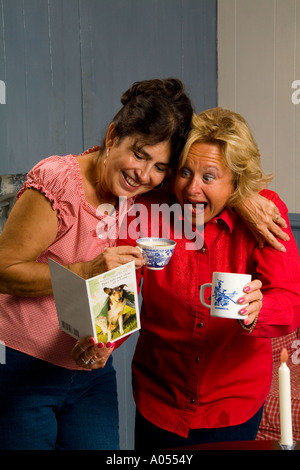 Small town women having coffee and laughing in the kitchen good friends relaxing at home together Stock Photo