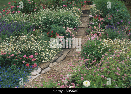 Cottage garden path in pink and pastel flowers with aggregate stone precast concrete pavers for easy access and care, USA Stock Photo