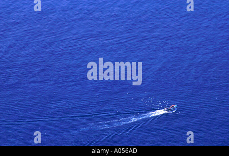 Local small fishing boat, netting fish off the Amalfi Coast for sale in the local market, is pursued by a small flock of seabird Stock Photo