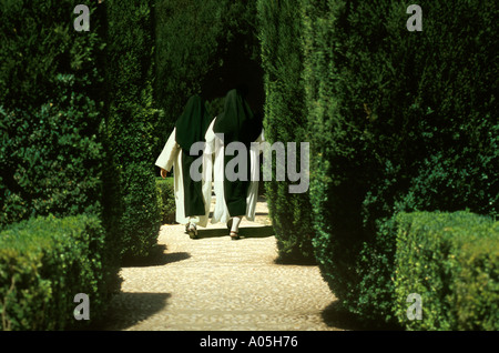 Two Catholic nuns wearing habits walking along a path through a garden Alhambra Palace Granada Spain Stock Photo
