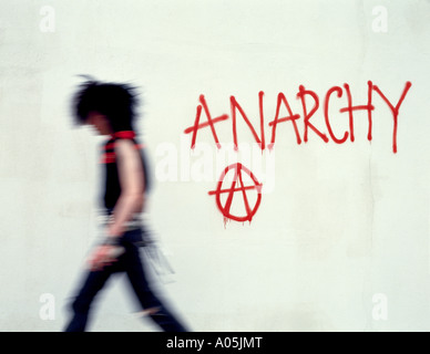 Punk type character walking away from spraying grafitti on a wall Stock Photo