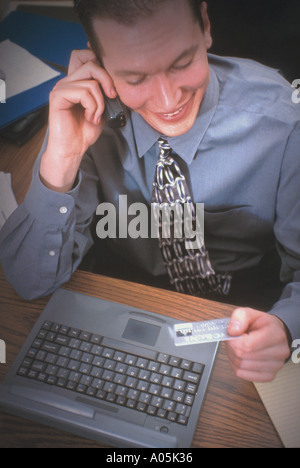 A businessman orders goods using his cell phone and paying with his credit card Stock Photo