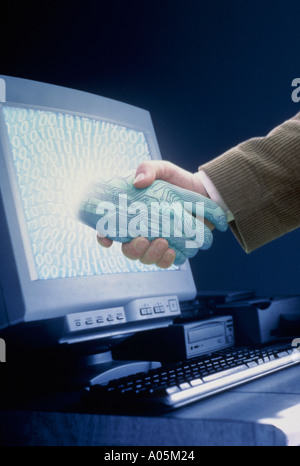 Computer generated image of a man hand shaking hands with a digital hand protruding from the computer monitor Stock Photo