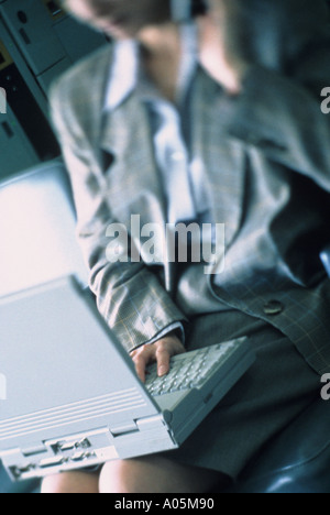 Out of focus businesswoman using her laptop in an airport as she travels for work Stock Photo