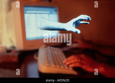 Hands on a keyboard with a digital hand protruding from the computer monitor Stock Photo