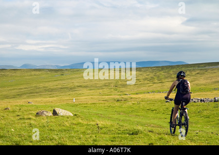 Female mountain biker on Crosby Ravensworth Fell in Cumbria with the Howgill Fells on the skyline Stock Photo