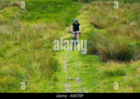 Female mountain biker on a track on Bluecaster Side near Sedbergh in Cumbria Stock Photo