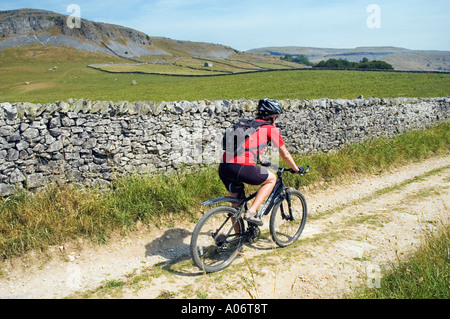 Female mountain biker on a track between Clapham and Austwick in the Yorkshire Dales Stock Photo