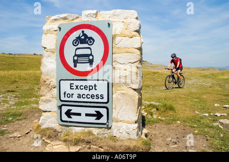 Female mountain biker rides past sign barring motor vehicles on a green lane Clapham Lane in the Yorkshire Dales Stock Photo