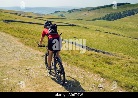 Female mountain biker descends into the valley of Clapham Beck in the Yorkshire Dales Stock Photo