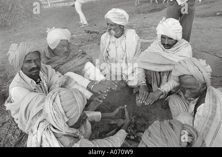 Five men sitting around wood fire on cold wintry morning at Voutha fair Gujrat India Stock Photo