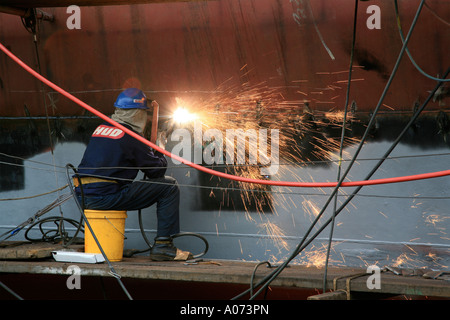 graphic detail shot of ship welder and ship welding  painting protective coating being applied at Hong Kong United Dockyard HUD Stock Photo