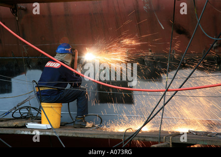 graphic detail shot of ship welder and ship welding  painting protective coating being applied at Hong Kong United Dockyard HUD Stock Photo