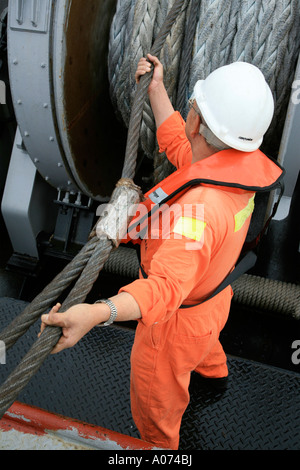 graphic shot of Tugboat sailor ready and pulling mooring rope seen through bollard at  Kwai Chung container port hong kong Stock Photo