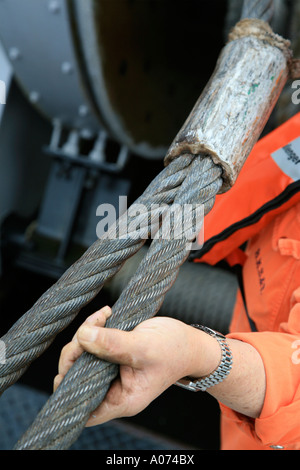 graphic shot of Tugboat sailor ready and pulling mooring rope seen through bollard at  Kwai Chung container port hong kong Stock Photo