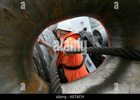 graphic shot of Tugboat sailor ready and pulling mooring rope seen through bollard at  Kwai Chung container port hong kong Stock Photo