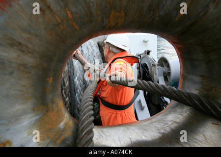 graphic shot of Tugboat sailor ready and pulling mooring rope seen through bollard at  Kwai Chung container port hong kong Stock Photo