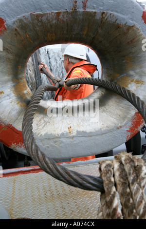 graphic shot of Tugboat sailor ready and pulling mooring rope seen through bollard at  Kwai Chung container port hong kong Stock Photo