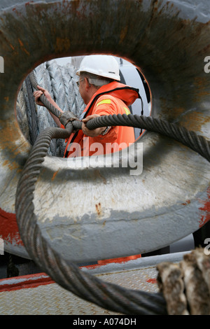 graphic shot of Tugboat sailor ready and pulling mooring rope seen through bollard at  Kwai Chung container port hong kong Stock Photo