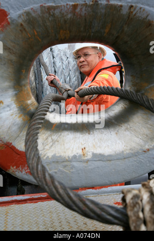 graphic shot of Tugboat sailor ready and pulling mooring rope seen through bollard at  Kwai Chung container port hong kong Stock Photo