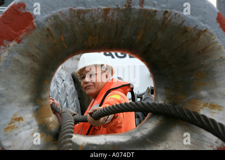 graphic shot of Tugboat sailor ready and pulling mooring rope seen through bollard at  Kwai Chung container port hong kong Stock Photo