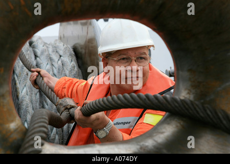 graphic shot of Tugboat sailor ready and pulling mooring rope seen through bollard at  Kwai Chung container port hong kong Stock Photo