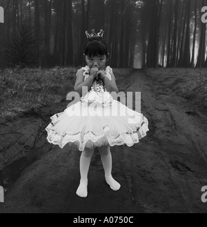 portrait young little princess multi Asian Japanese girl in ballerina ballet tutu and tiara scared face eyes in woods forest Stock Photo