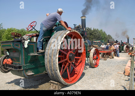 Close up steam traction engine man controlling steam power to drive a distant sawing bench working a large diameter belt driven saw blade England UK Stock Photo