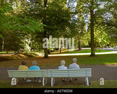 senior citizens old age pensioners OAP sitting on a bench in park a married couple and two women Stock Photo