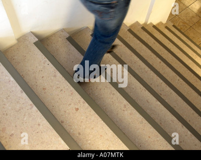 MR feet of a woman wearing sharp shoes and jeans in movement on stairs Stock Photo