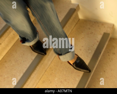 MR feet of a woman wearing sharp shoes and jeans in movement on stairs Stock Photo