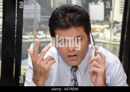 CEO worried talking on cellphone in his cabin with city background Stock Photo