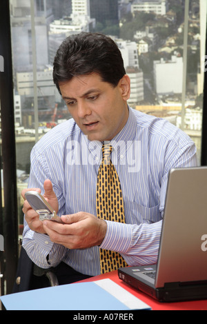 CEO on cellphone working on laptop in his cabin with city back ground Stock Photo