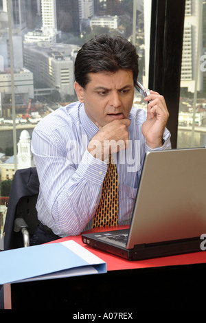 CEO on cell phone working on laptop in his cabin with city back ground Stock Photo