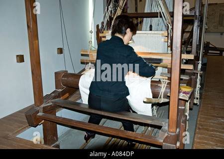 A female Chinese worker weaving silk at a loom in the No1 Silk Factory, Suzhou Stock Photo