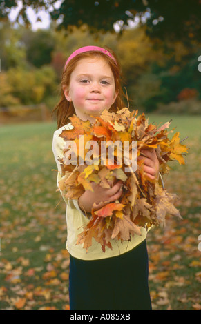 Portrait of young, four year old, redhead, girl playing with autumn foliage leaves, New England, Lexington, Massachusetts, USA. Stock Photo