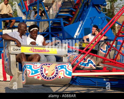 African American couple ride the Scrambler He appears to be having a lot of fun watching his anxious partner Stock Photo