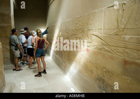 Tourists study ancient inscriptions inside a tomb at the Pyramid complex at Saqqara, near Cairo, Egypt, Africa. Stock Photo