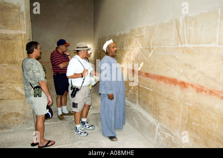 Tourists study ancient inscriptions inside a tomb at the Pyramid complex at Saqqara, near Cairo, Egypt, Africa. Stock Photo