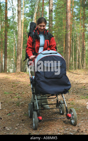 Mother walking with baby carriage in forest. Altai. Siberia. Russia Stock Photo