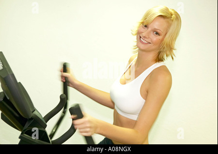 Junge Frau trainiert im Fitnessraum eines Vital Hotels, Young woman working out at the gym of a vital hotel Stock Photo