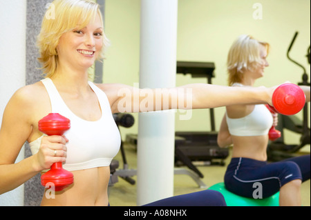 Junge Frau trainiert im Fitnessraum eines Vital Hotels, Young woman working out at the gym of a vital hotel Stock Photo