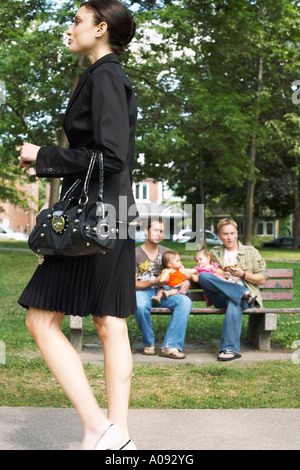 Woman Walking past Men with Babies in Park