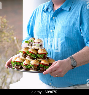 Man Carrying Plate of Small Hamburgers Stock Photo