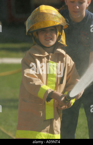 Young boy and a women fire fighter using the fire hose for an fire fighter exercise Stock Photo