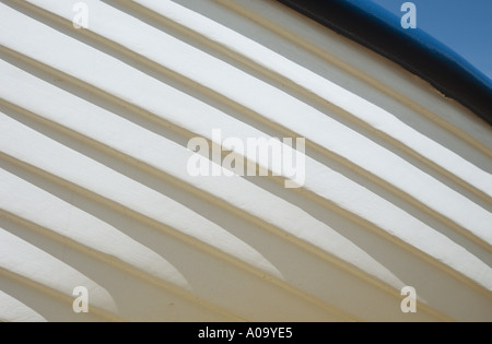 Detail viewed from below of the white hull of a wooden boat with blue sky visible above Stock Photo