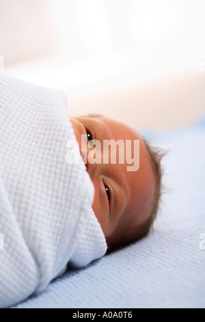 Newborn baby in bed wrapped in blanket Stock Photo